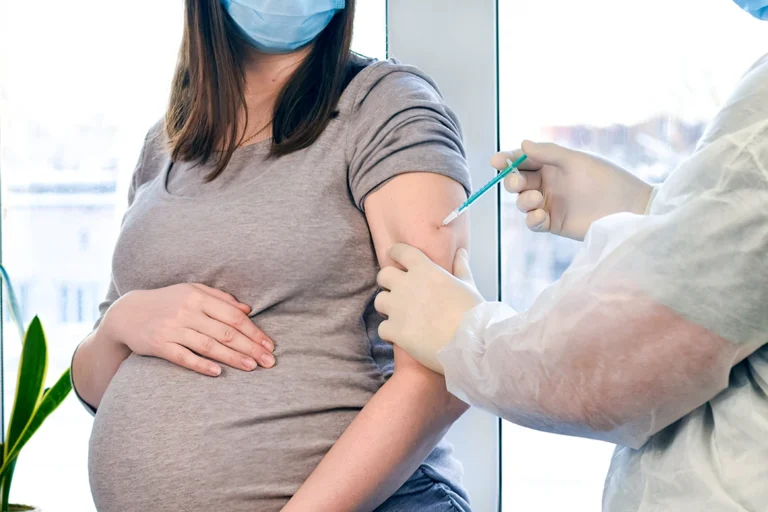 maternal vaccination study - doctor injecting vaccine in shoulder of pregnant woman